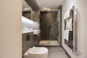 Un baño moderno con ducha de vidrio, inodoro y toallero.