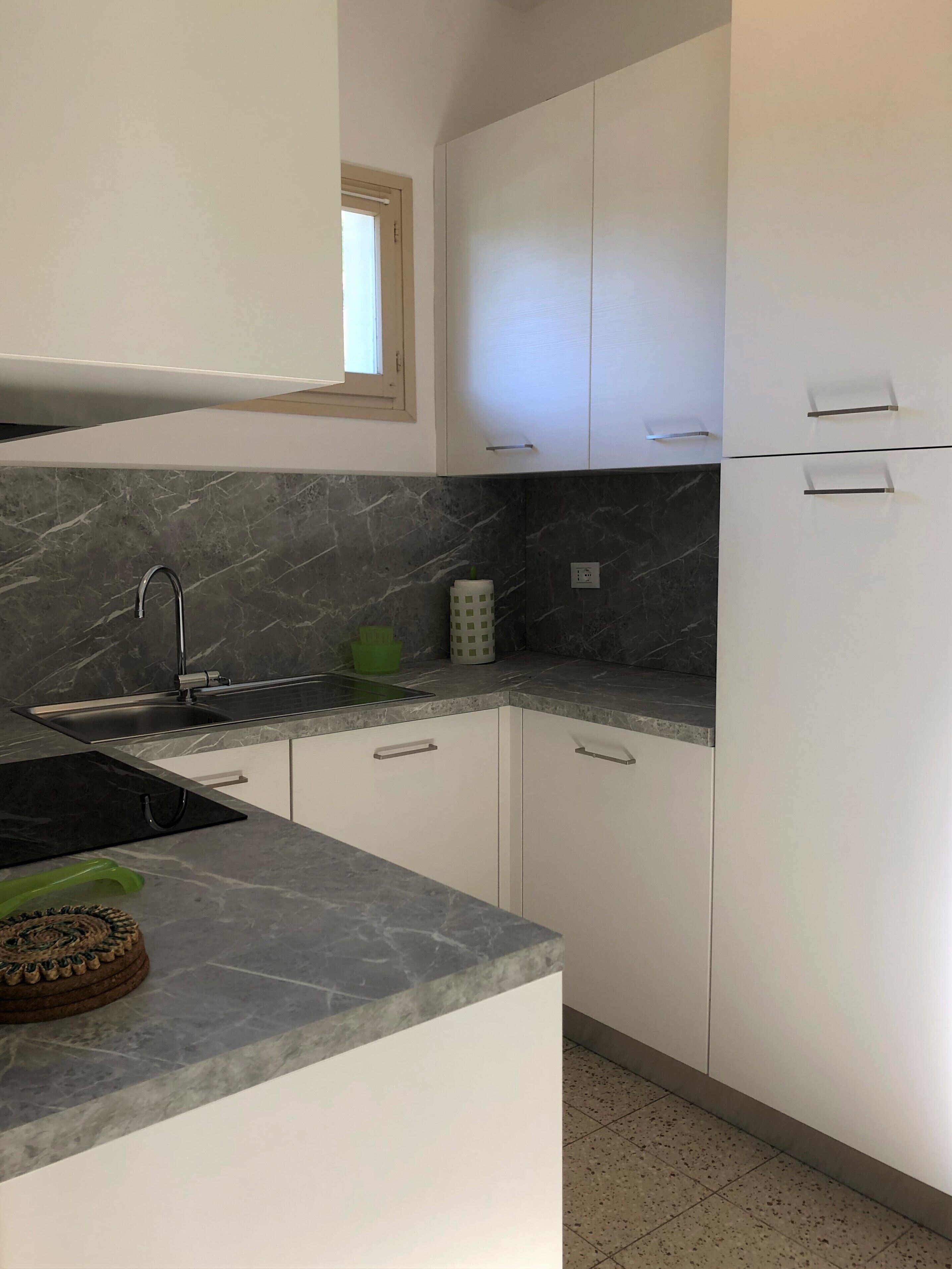 A kitchen with white cabinets, a marble countertop, and a sink.