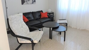 Un soggiorno moderno con un divano in pelle nera, una poltrona bianca, un tavolino rotondo e una lampada da terra.