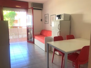 A compact living space with a kitchenette, a dining area, and a balcony.