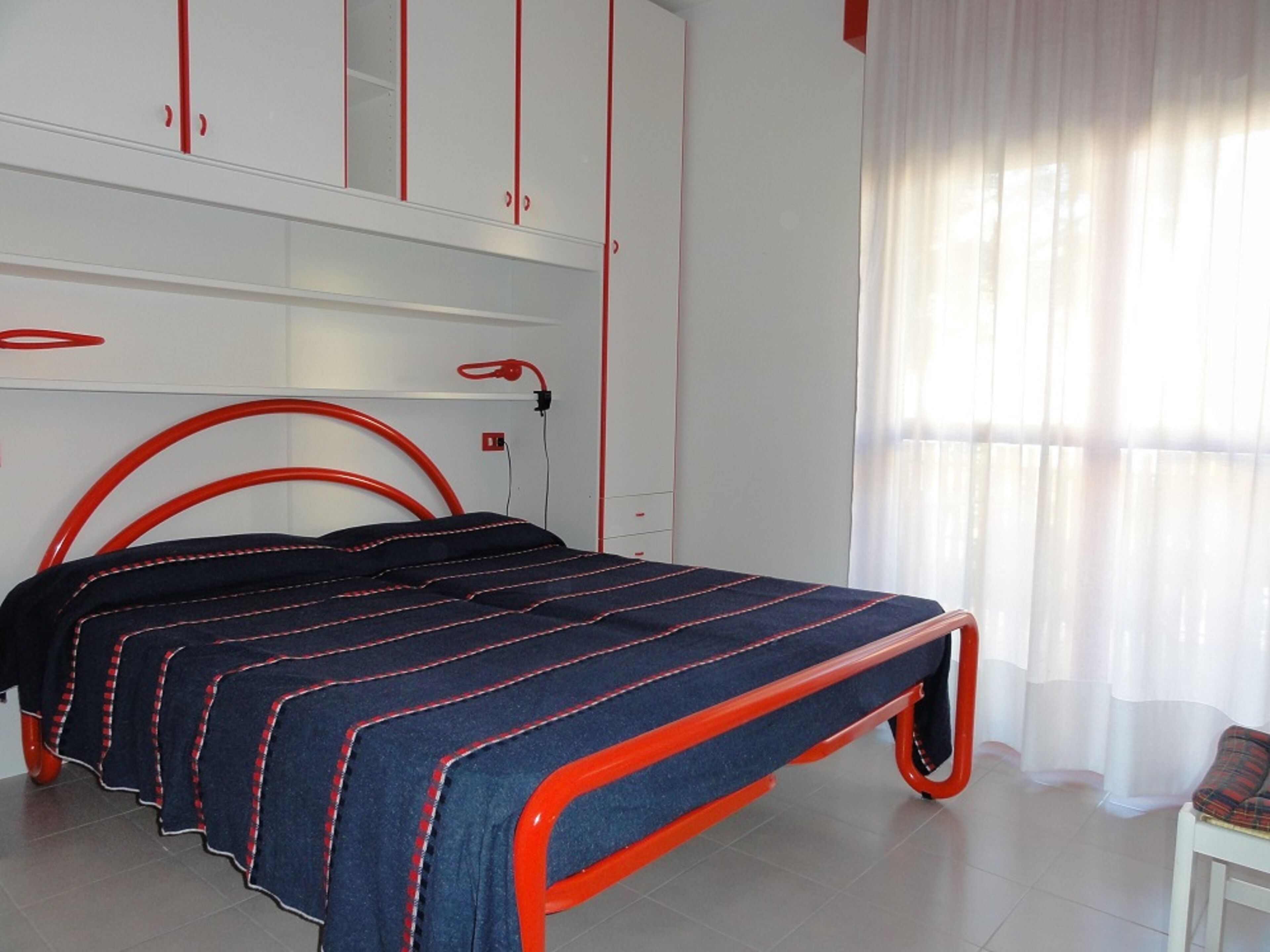 A bedroom with a bed, a wardrobe, and a window with curtains.