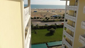 A balcony with a view of a beach and a parking lot. - Bibione Apartment With Side sea View (San Michele al Tagliamento)
