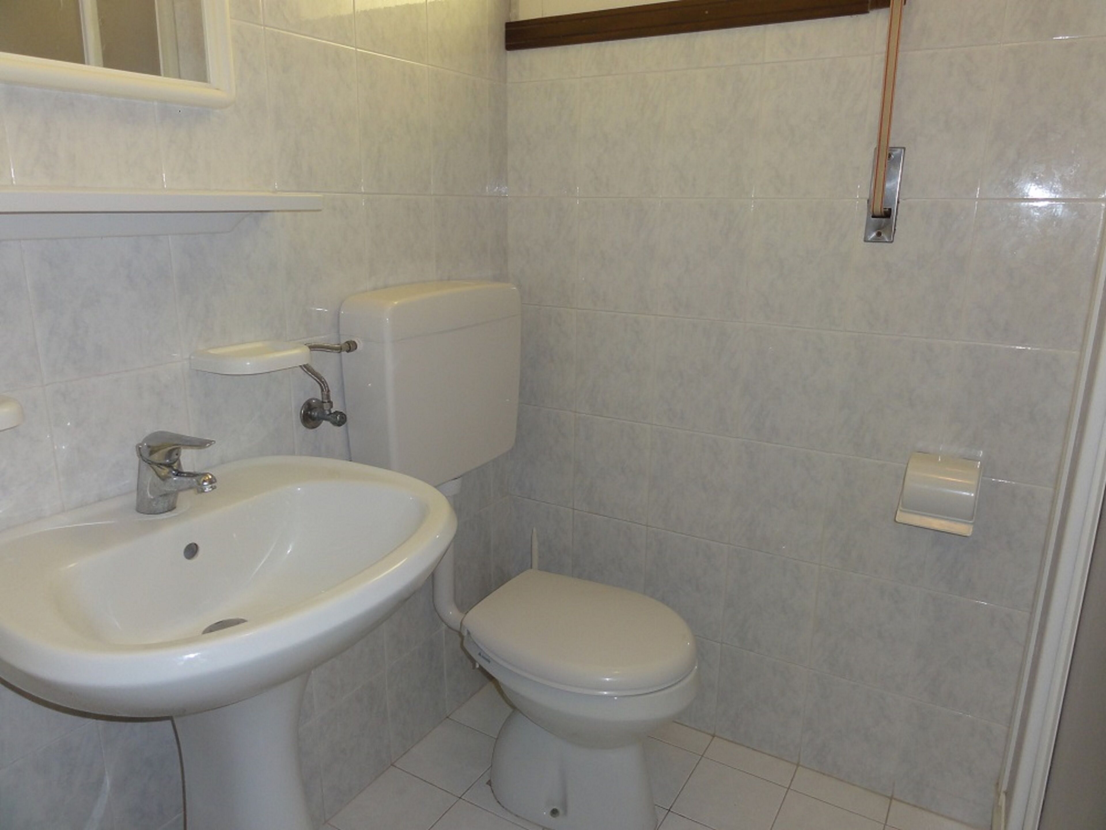 Ein Badezimmer mit einem weißen Waschbecken, einer Toilette und einem Spiegel über dem Waschbecken.