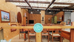 A rustic wooden interior with a 'Chill Out Zone' sign, wooden furniture, and a cozy atmosphere. - Cwtch Bach (Aberdare)