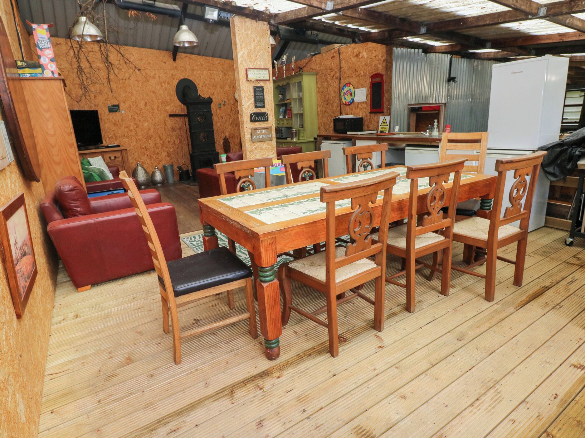 A wooden dining table with six chairs, a red sofa, and a wooden cabinet in a rustic interior.