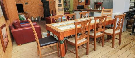 A wooden dining table with six chairs, a red sofa, and a wooden cabinet in a rustic interior.