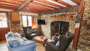 A cozy living room with a stone fireplace, wooden beams, and comfortable seating.