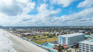 Un hotel frente al mar con piscina, acceso directo a la playa y vistas al horizonte de la ciudad.