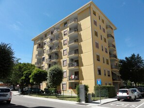 Ein mehrstöckiges Wohngebäude mit Balkonen, einem Parkplatz und blauem Himmel.
