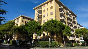 A multi-story residential building with balconies, surrounded by trees and a clear sky. - Great Flat Close to the sea (San Michele al Tagliamento)