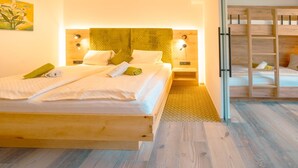 A bed with a wooden frame, a headboard with integrated lighting, and a bedside table. - Familienhotel Unterreith (Forstau)