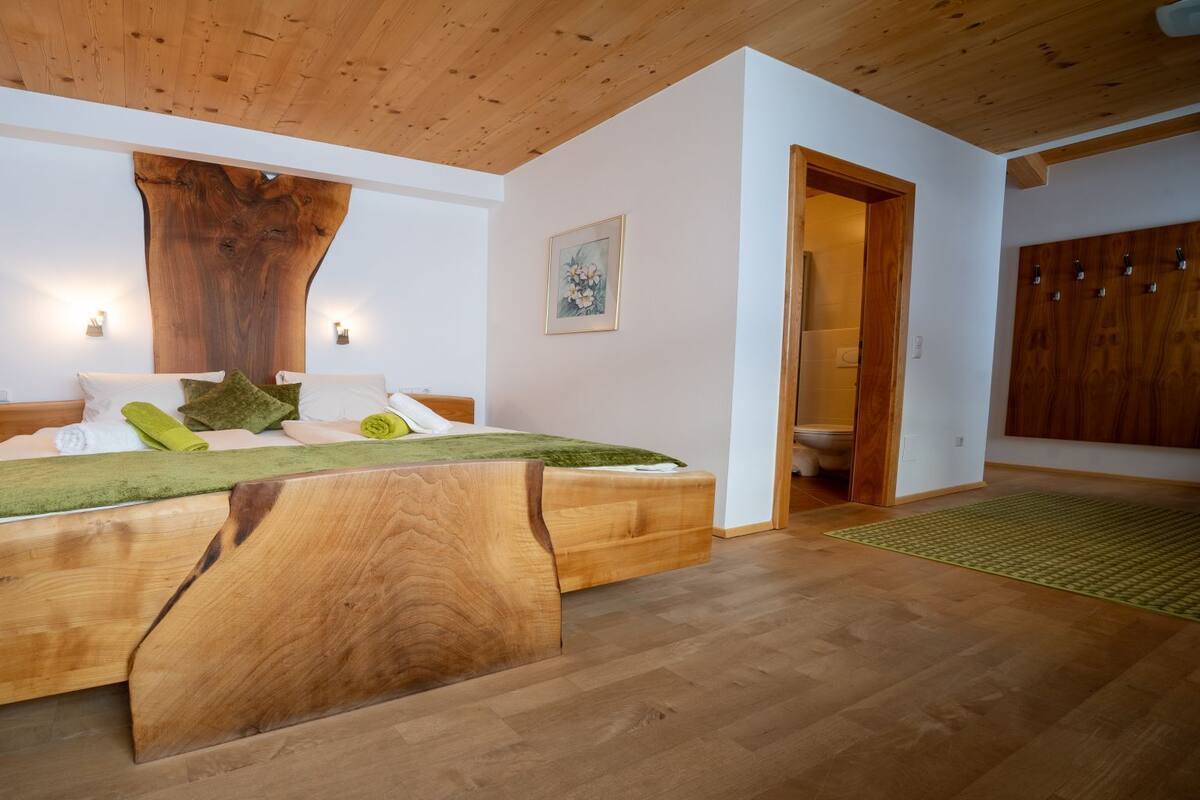 Ein Schlafzimmer mit einem großen hölzernen Bett, einer Holzbalkendecke und einem Holzschrank.
