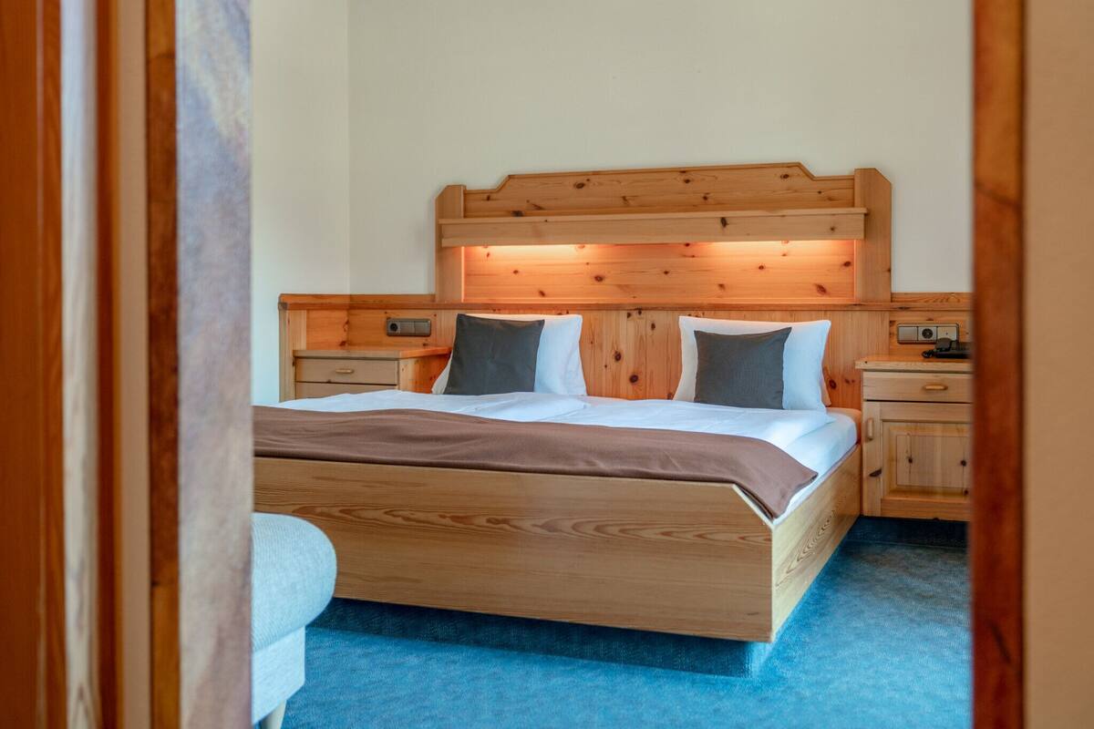 Ein hölzernes Bett mit Kopfteil, zwei Nachttischen und einem Beistelltisch.