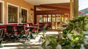 A restaurant with outdoor seating, wooden beams, and a view of the surrounding landscape. - Familienhotel Unterreith (Forstau)