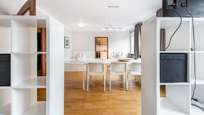 Een modern interieur met witte muren, een houten vloer, een eethoek met stoelen en een tafel, en ingebouwde kasten.