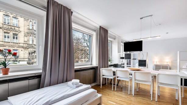 Een moderne hotelkamer met een bed, bureau, stoelen en een televisie.