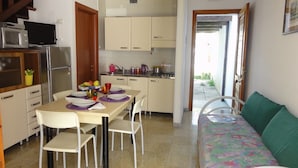 A compact kitchen with a dining table set for four, a sofa, and a microwave on the counter. - Comfy Terraced House (San Michele al Tagliamento)
