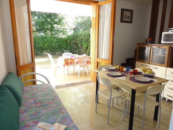 A cozy room with a sofa, a dining table set for four, and a kitchen area with a microwave.