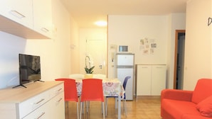 Um espaço compacto com área de refeições, cozinha compacta e sofá vermelho.