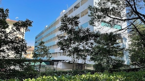 Um edifício com várias andares e varandas, rodeado por vegetação e árvores.