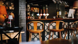A bar area with wooden chairs, a bar counter, and a lamp. - The Greyhound on the Test (Stockbridge)