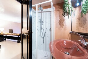 A modern bathroom with a glass shower enclosure, a red sink, and a hanging plant. - Rental in Rome Navona Loft (Rome)