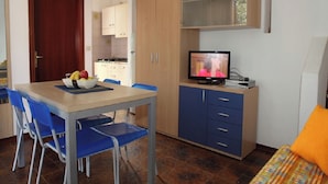 A compact living space with a dining area, kitchenette, and a television. - Townhouse With Private Garden (San Michele al Tagliamento)