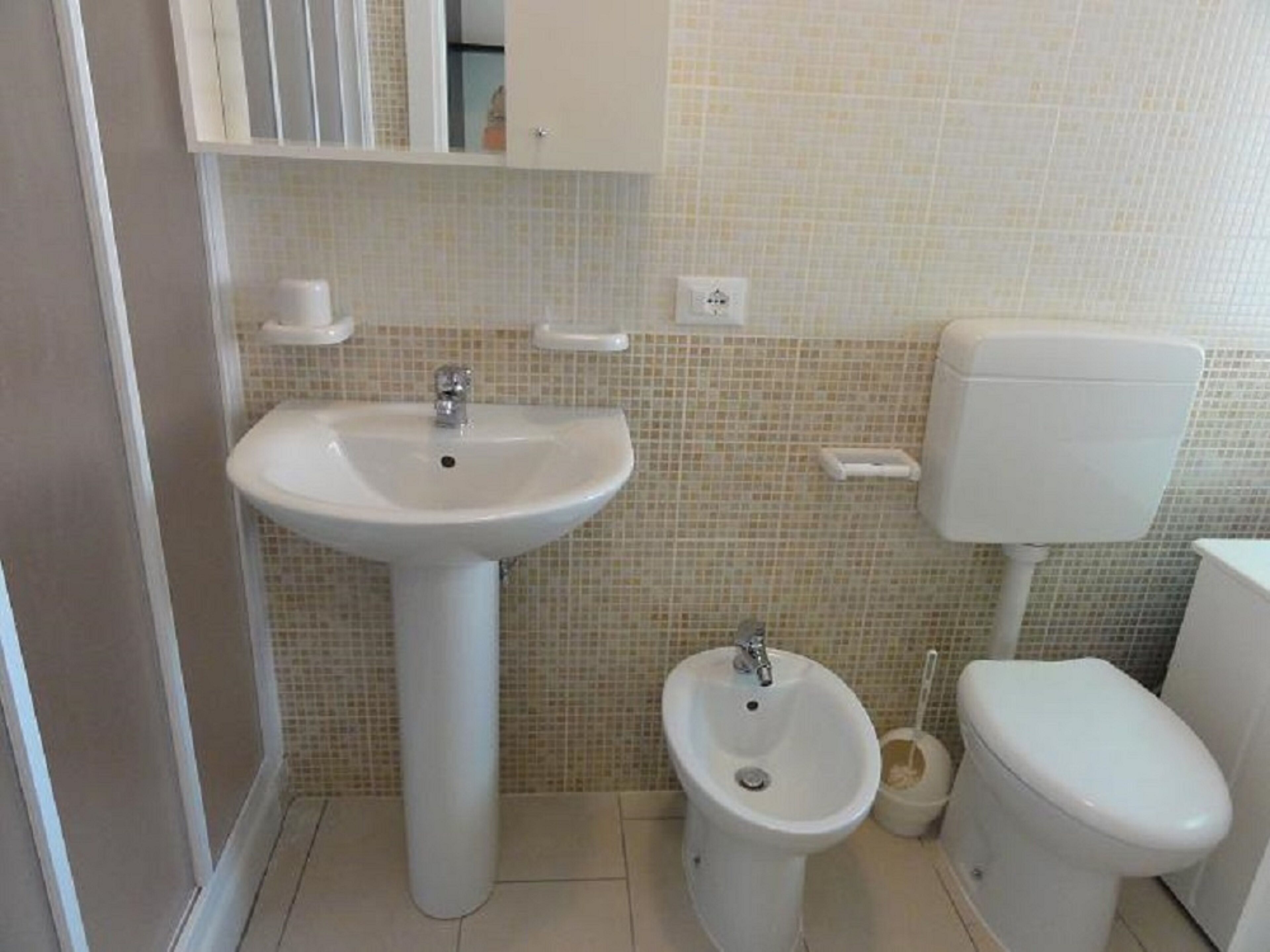 Ein Badezimmer mit einem Standwaschbecken, einem Bidet und einer Toilette.