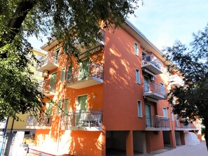A multi-story building with balconies, a flat roof, and a visible entrance.