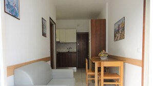 A compact living space with a kitchenette, a dining table with chairs, and a sofa. - Comfortable Stay Near the Promenade and Shops (San Michele al Tagliamento)