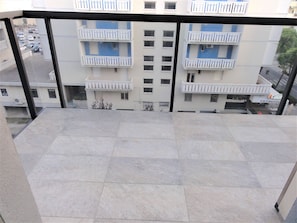 A balcony with a tiled floor, overlooking a building with multiple balconies and windows. - Comfortable Stay Near the Promenade and Shops (San Michele al Tagliamento)
