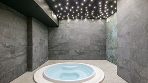 Un cuarto de spa con hidromasaje, paredes de azulejos y un techo con luces que simulan estrellas.