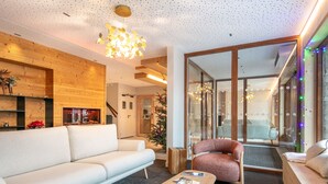 Una sala de estar moderna con un sofá, una mesa de centro con revistas, una chimenea y un árbol de Navidad.