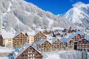 Un complejo turístico en la montaña cubierto de nieve, con chalés de madera y un telesilla.
