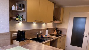 Een kleine keuken met houten kastjes, een spoelbak, een koffiezetapparaat en een broodrooster.