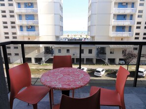 A balcony with a round table and four chairs, overlooking a parking area and buildings with balconies. - Relaxing sea View Stay Near the Promenade (San Michele al Tagliamento)