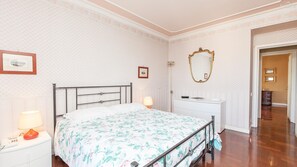 Ein Schlafzimmer mit einem Bett, Nachttischlampen, einem Schminktisch, einem Spiegel und einem gerahmten Bild an der Wand.