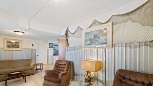 Ein Wohnzimmer mit einem braunen Sessel, einer Couch, einem Glastisch und einer Lampe.