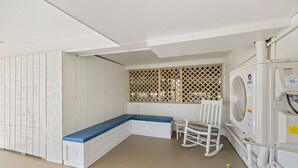 Ein Zimmer mit einer weißen Bank, einem Schaukelstuhl und einem Fenster mit Gitterverkleidung.