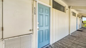A row of white buildings with a blue door, numbered 312, and a wooden porch. - Top Floor 🪸 Private Balcony 🪸 View of the Gulf (Cedar Key)