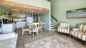 A spacious living area with a dining table, chairs, a sofa, and a staircase leading to another level. - Top Floor 🪸 Private Balcony 🪸 View of the Gulf (Cedar Key)