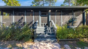 A covered outdoor area with steps leading to a seating area, surrounded by greenery. - Cedar Key Seaside Escape (Cedar Key)