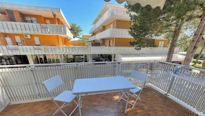 A patio with a table and chairs, a white fence, and buildings in the background.