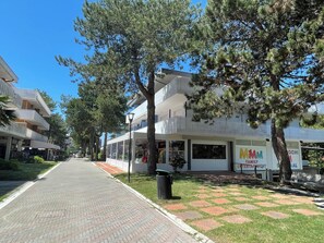 A street with buildings, trees, and a paved walkway. - Nice Studio Near the Beach in Bibione (San Michele al Tagliamento)