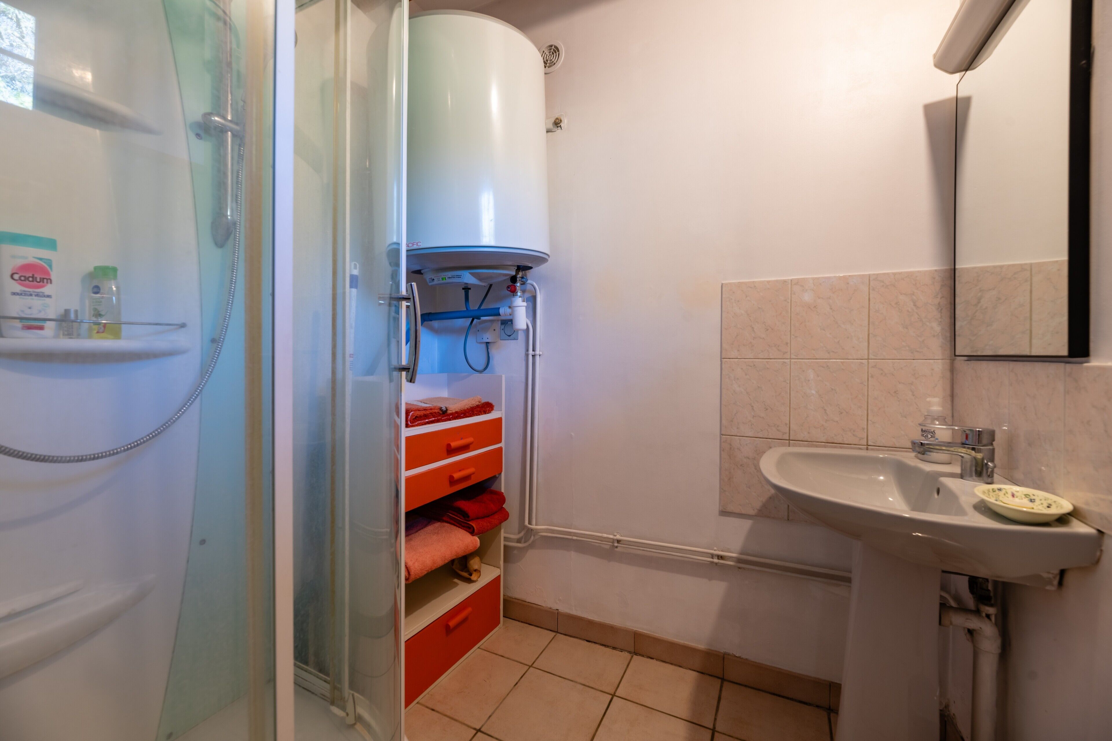 A bathroom with a shower, a sink, and a towel rack.