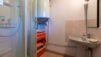 A bathroom with a shower, a sink, and a towel rack.