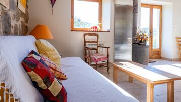 A bedroom with a bed, a chair, a table, a window, and a fireplace.
