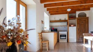 A kitchen with wooden beams, a white refrigerator, a stove, and a chair. - Le Mas Victor Ardèche – Tranquility and Nature Near Saint-Victor (saint victor)