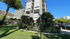 A multi-story residential building with balconies, surrounded by well-maintained lawns and trees. - Bibione Flat With Side sea View (San Michele al Tagliamento)