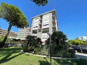 Un edificio residenziale a più piani con balconi, circondato da prati curati e alberi.